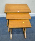 NATHAN FURNITURE, A MID-CENTURY TEAK NEST OF THREE TABLES, raised on cross shaped legs, largest
