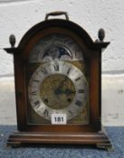 A HERMLE MOONPHASE MANTEL CLOCK, with a carry handle and four finials to the arched top, the glass
