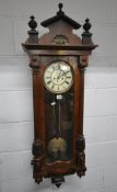 AN EARLY 20TH CENTURY MAHOGANY CASED VIENNA WALL CLOCK, the shaped pediment with three finials, over