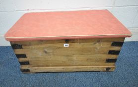 A CORONA PINE STORAGE CHEST, with a pink upholstered cushion, and metal banding, width 78cm x