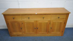 A MODERN SOLID OAK SIDEBOARD, fitted with three drawers, over four cupboard doors, length 183cm x