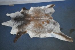 A LARGE BROWN AND WHITE COWHIDE RUG, approximately 240cm x 195cm, condition report: some wear,