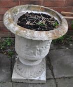 A CONCRETE GARDEN URN, with cherub detail to balustered bowl and a fluted footing, height 63cm