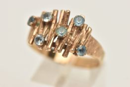 A 9CT GOLD BRUTALIST RING, textured effect set with six circular cut blue stones assessed as