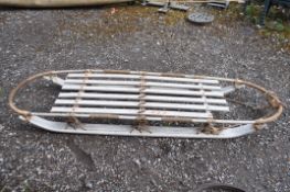 A MID CENTURY WOODEN SLED, with rope bindings, a bentwood top rail and curved skids