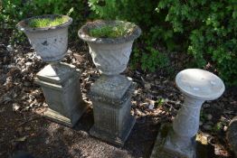 A PAIR OF WEATHERED COMPOSITE GARDEN URNS, with lattice detail, on a separate square plinth,