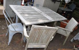 A LARGE WEATHERED HARDWOOD GARDEN TABLE, two similar carver chairs, and a set of four stacking metal