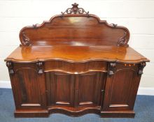A VICTORIAN MAHOGANY SIDEBOARD, the raised back with scrolled and foliate details, a serpentine