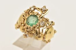 A YELLOW METAL EMERALD AND DIAMOND ABSTRACT DRESS RING, set with a central oval cut emerald, claw