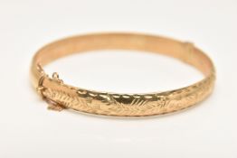A 9CT GOLD HINGED BANGLE, foliate pattern to one side, fitted with an integrated push piece clasp,