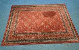 ROYAL KESHAN, A RED GROUND WOOLEN RUG, with repeating foliate patterns, surrounded by a multi-