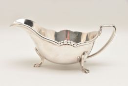 A SILVER PLATE 'HARRODS' SAUCE BOAT, polished form raised on three paw feet with a handle, signed to