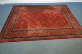 ROYAL KESHAN, A RED GROUND WOOLEN RUG, with repeating foliate patterns, surrounded by a multi-