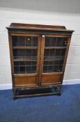 AN EARLY 20TH CENTURY OAK BOOKCASE, with double lead glazed doors, raised on spiral supports, united