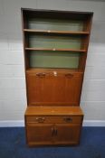 G PLAN, A MID-CENTURY TEAK BOOKCASE, with a fall front door, atop a base with a single drawer,