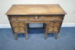 AN EARLY 20TH CENTURY OAK KNEEHOLE DESK, fitted with six assorted drawers, with geometric