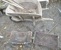 A VINTAGE WOODEN WHEEL BARROW, height 73cm, a quantity of gardening tools, cast iron fire dogs, a