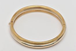 A 9CT GOLD BANGLE, a white and yellow gold hollow bangle, fitted with an integrated push pin
