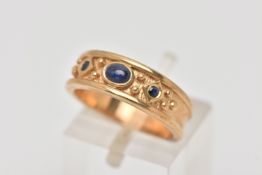 A 9CT GOLD GEM SET RING, a tapered textured band ring with beading detail, set with three small blue
