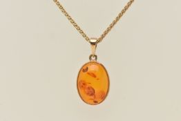 A 9CT GOLD PENDANT, an oval copal amber, collet set in yellow gold, hallmarked 9ct London, suspended