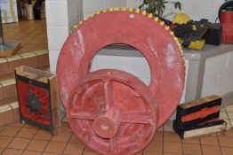 A GROUP OF WOODEN GEARS FOR DISPLAY PURPOSES painted in black, red and yellow, largest diameter
