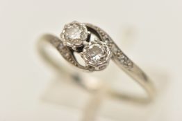 A WHITE METAL DIAMOND CROSS OVER RING, two illusion set round brilliant cut diamonds, between single