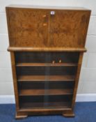 AN ART DECO WALNUT COCKTAIL CABINET, the double cupboard doors enclosing a mirrored interior, over