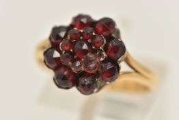 A YELLOW/WHITE METAL CLUSTER RING, designed as a tiered bohemian garnet cluster, mounted in a