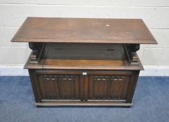 A 20TH CENTURY OAK MONKS BENCH, with a hinged surface, that’s resting on lion armrests, flanking a