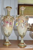 A NEAR PAIR OF ROYAL WORCESTER TWIN HANDLED PEDESTAL VASES, shape no 1410, with twin mask handles,