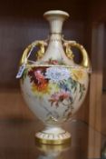 A ROYAL WORCESTER BLUSH IVORY TWIN HANDLED VASE, of urn form with gilt handles terminating in a