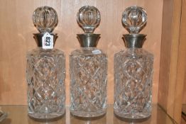 A SET OF THREE CUT GLASS DECANTERS, with stoppers and silver collars, round in form, hallmarked