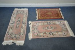 A PAIR OF PINK GROUND CHINESE WOOLEN RUGS, 130cm x 61cm, along with a smaller rug, condition report: