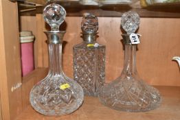 THREE CUT GLASS DECANTERS, with stoppers and silver mounts, comprising a ship's decanter with