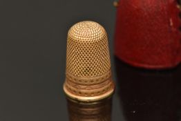 A YELLOW METAL CASED THIMBLE, a yellow metal thimble with wave and grain detail, approximate gross