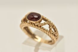 A YELLOW METAL GEM SET RING, an oval cabochon, collet set in yellow metal, tapered open work band