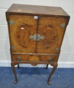 AN EARLY 20TH CENTURY WALNUT COCKTAIL CABINET, the double doors enclosing a fitted interior, over