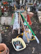A BUILDERS WHEELBARROW CONTAINING GARDEN TOOLS, including chimney rods, a hose reel, spades,