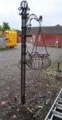 A WROUGHT IRON HANGING BASKET STAND, with one basket base and three rotating arms holding baskets,