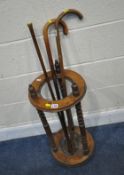 A 20TH CENTURY OAK CYLINDRICAL STICK STAND, with three finials, raised on bobbin turned supports,