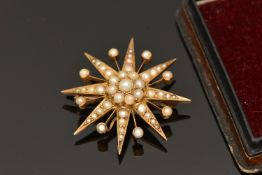 AN EARLY 20TH CENTURY PEARL BROOCH, a yellow metal star brooch with cluster design centre, set