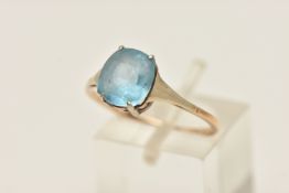 A YELLOW METAL PASTE RING, an oval cut blue paste stone, prong set in yellow metal, white metal