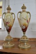 A PAIR OF ROYAL WORCESTER TWIN HANDLED PEDESTAL VASES AND COVERS, shape no 1957, of slender form,