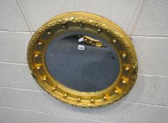 A REGENCY STYLE GILT WOOD CIRCULAR WALL MIRROR, possibly early 19th century frame with later