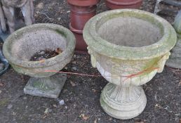 A CONCRETE CAMPAGNA GARDEN URN, with twin mask decorated handles, on a separate circular base,