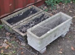 A CONCRETE RECTANGULAR PLANTER, on twin supports, decorated with mythical decoration, along with two
