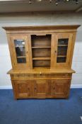 A SOLID OAK DRESSER, the top with two glazed doors, flanking two shelves, atop a base with three