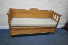 A LARGE PINE SETTLE, with scrolled armrests, and a hinged seat, length 184cm x depth 53cm x height