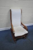 A VICTORIAN MAHOGANY ROCKING CHAIR, with scrolled armrests, raised on turned front supports, width