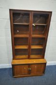 A MID-CENTURY TEAK BOOKCASE, the double glazed doors enclosing three shelves, atop a base with